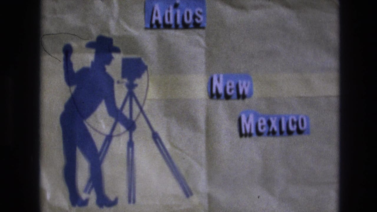 1973 New Mexico 8mm frame of a handmade farewell title card with a cowboy in profile operating a tripod camera and purple “Adios New Mexico” lettering.
