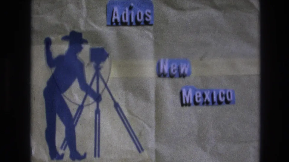 1973 New Mexico home-movie title card reading Adios New Mexico beside a blue silhouette of a cowboy operating a camera on a tripod.