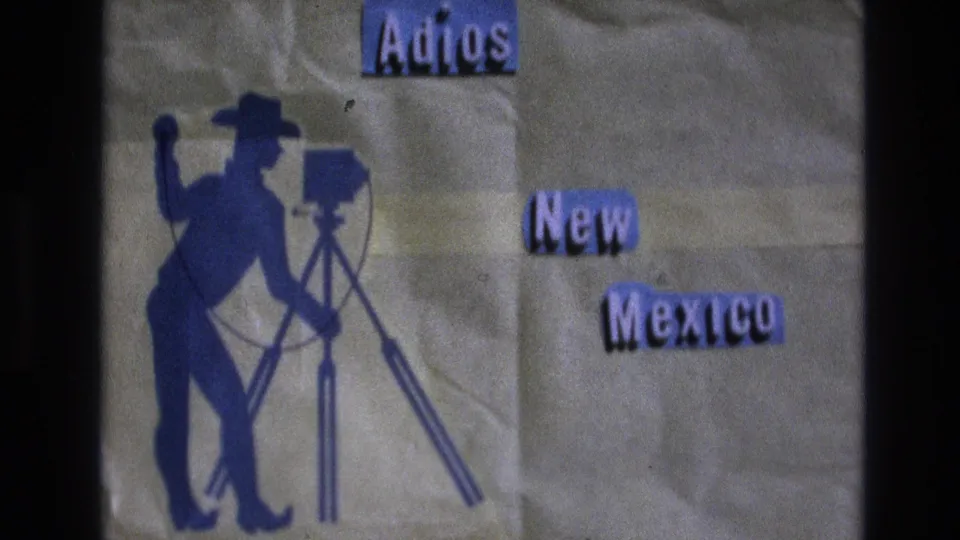 Soft 8mm frame of a handmade 1973 New Mexico farewell title card with a cowboy cameraman silhouette and raised-looking cut-out words.