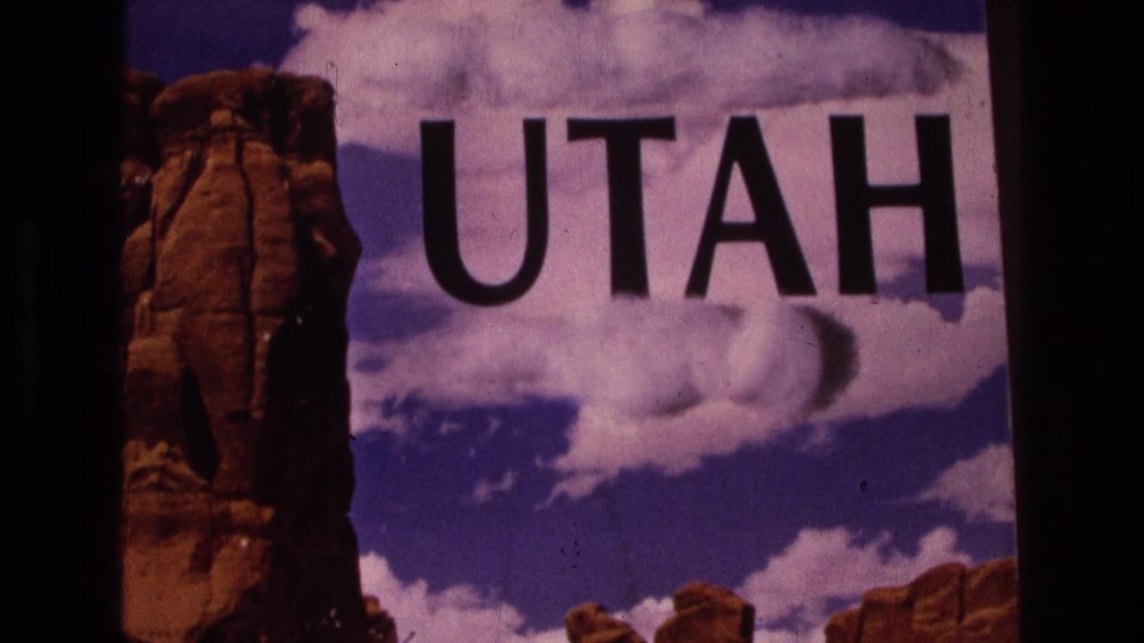 Large UTAH lettering over red rock formations and a cloudy blue sky.