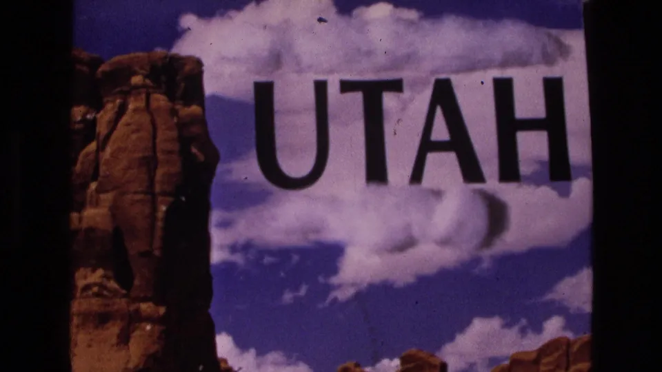 1973 Utah title frame with bold black lettering, red rock scenery, blue sky, and visible 8mm film texture.