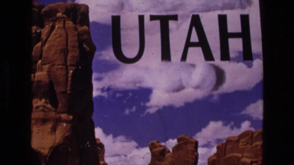 1973 Utah travelogue frame showing large black UTAH lettering above red rock formations under a bright blue sky with clouds.