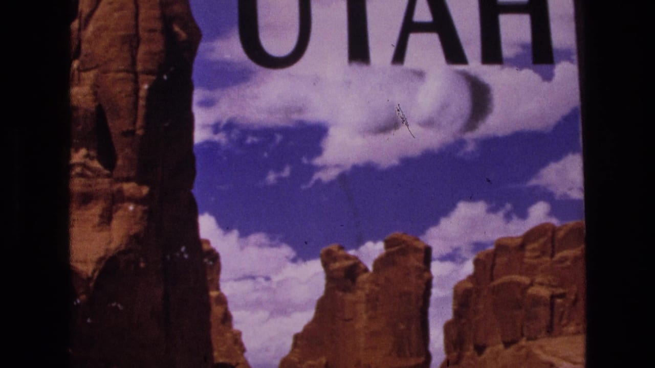 1973 8mm frame with partial UTAH text, red rock spires, blue sky, and visible contact-sheet film edges.