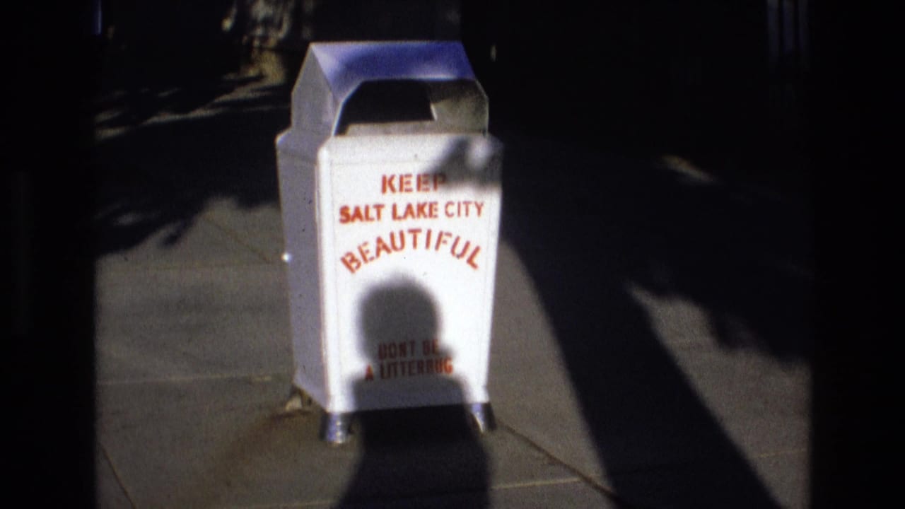 White litter container with red Salt Lake City beautification text beside a sidewalk shadow.