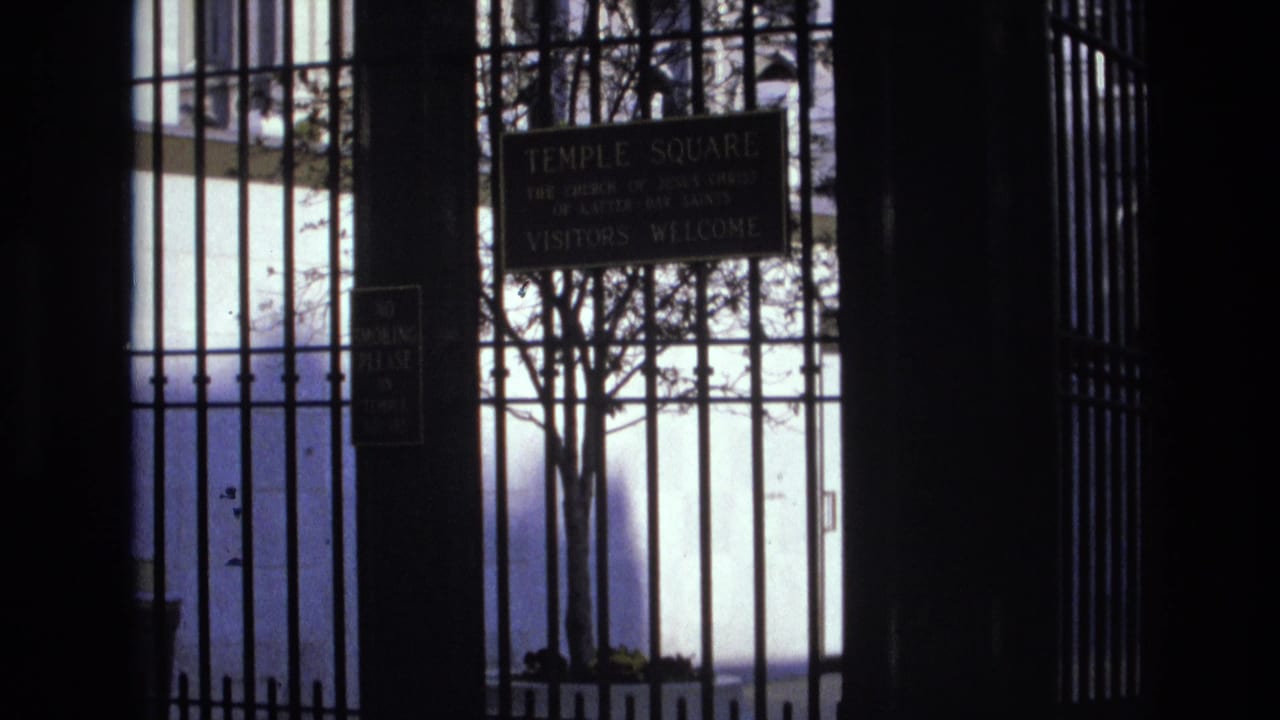 Temple Square sign behind iron gate bars with tree branches and bright exterior light.