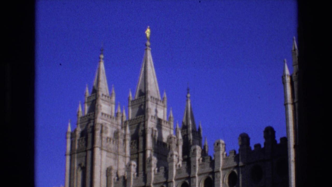 Stone temple spires against a clear blue sky, partly framed by dark vertical edges.