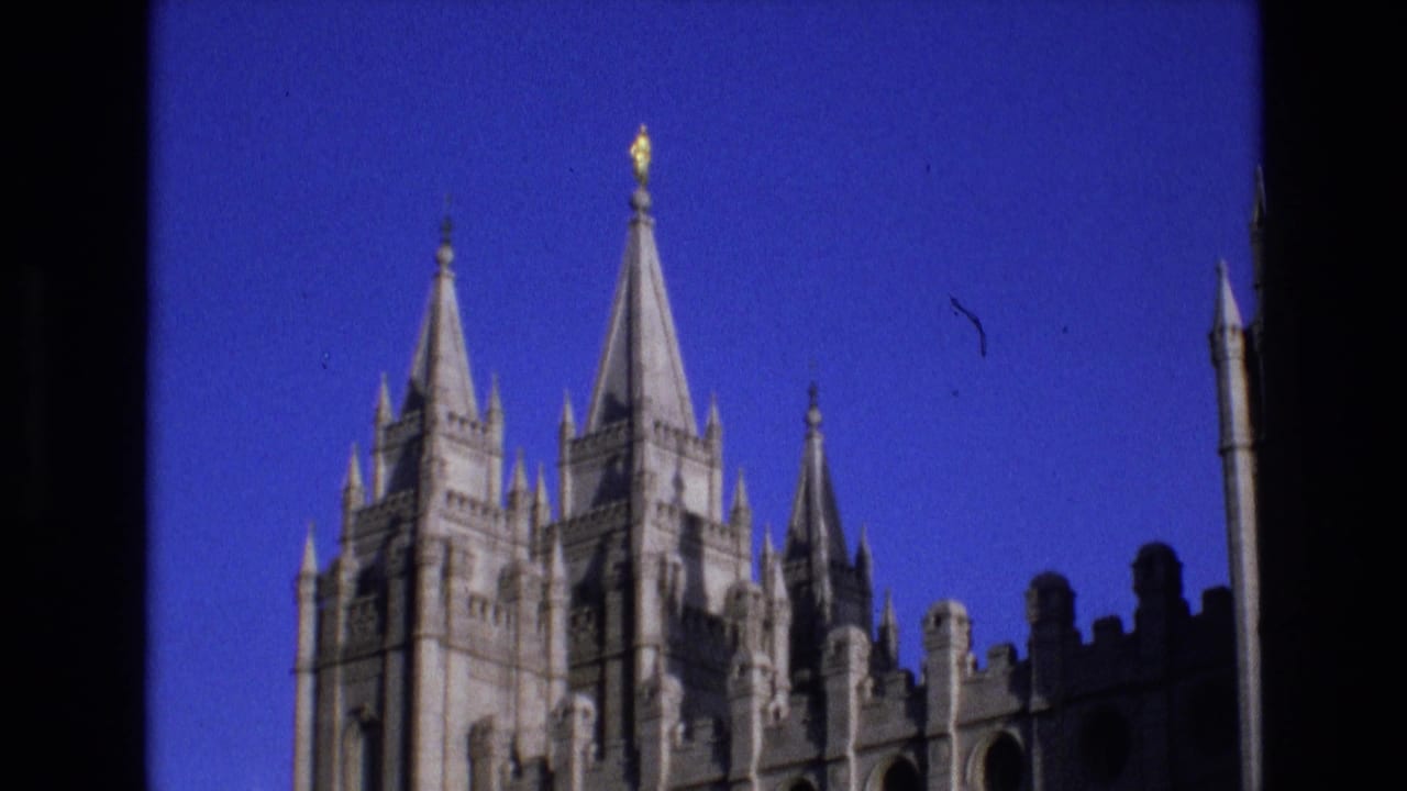 Salt Lake City Temple towers and roofline details in 1973 8mm footage, with the building partially bordered by dark window or structural edges.