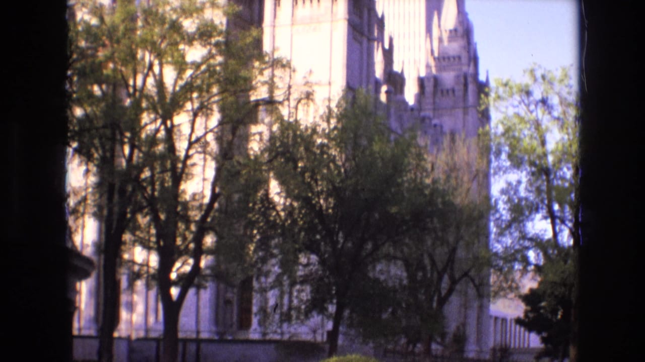 1973 Salt Lake City 8mm frame showing a pale stone urban building behind trees, with dark edge vignetting from the film scan.