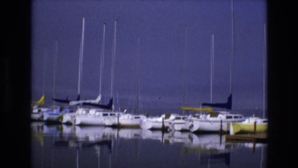 Soft 8mm frame of docked sailboats in Salt Lake City, Utah, with bright hulls, tall masts, and quiet water reflections.