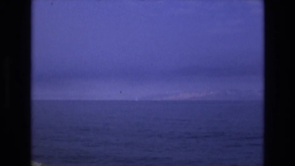 1973 8mm Salt Lake City-area footage showing dark calm water, a low distant horizon, and blue twilight sky with visible film-frame borders.