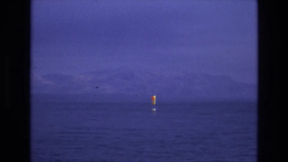 1973 Salt Lake City, Utah 8mm frame showing a small red and yellow buoy flag on calm water beneath a hazy sky and faint mountain horizon.
