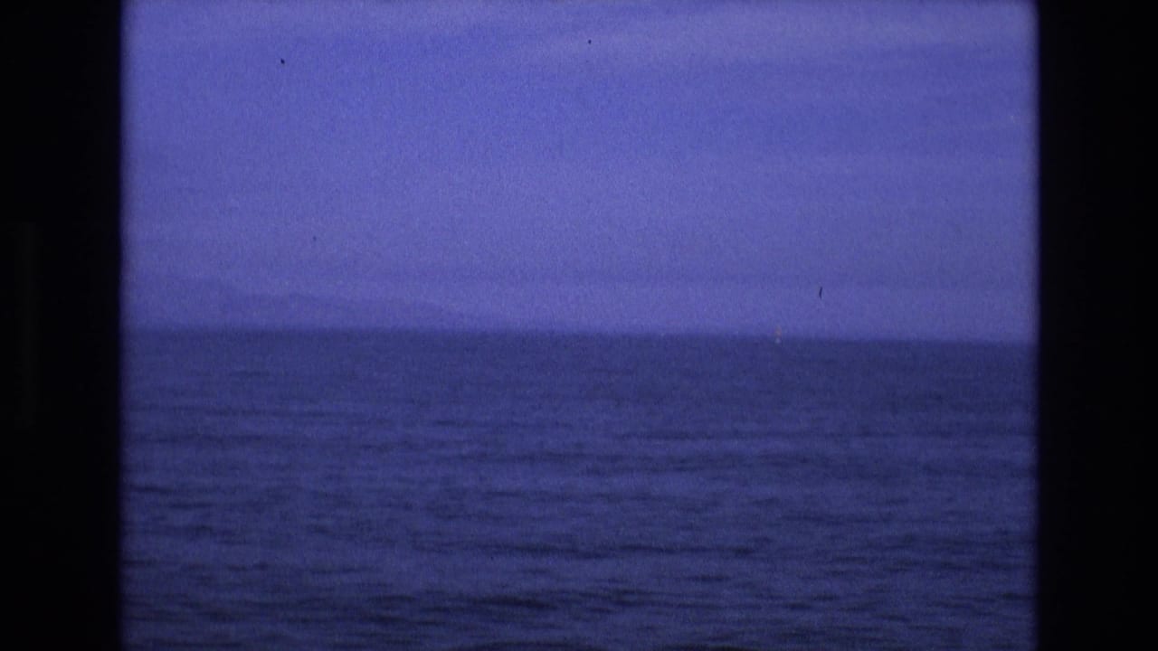 Dark blue ocean waves beneath a dim sky, framed by black vertical borders.