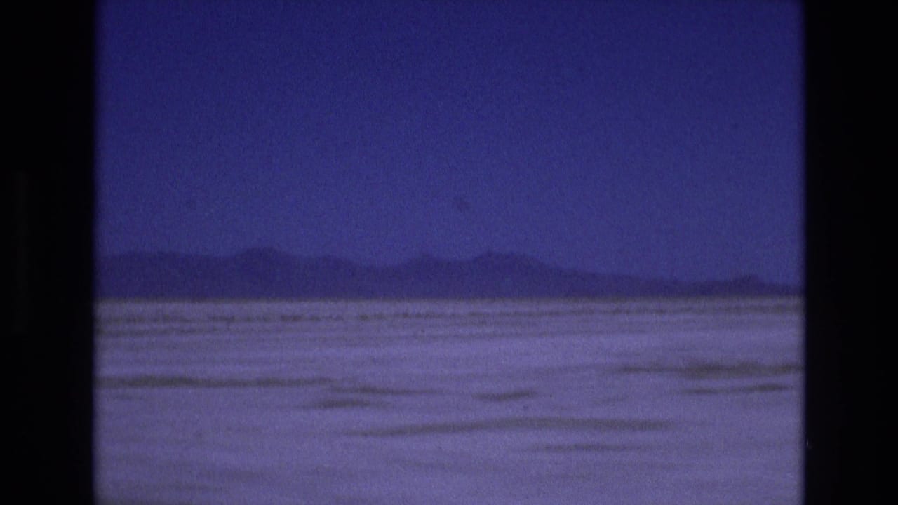 Flat pale basin with distant mountains under a deep blue sky.