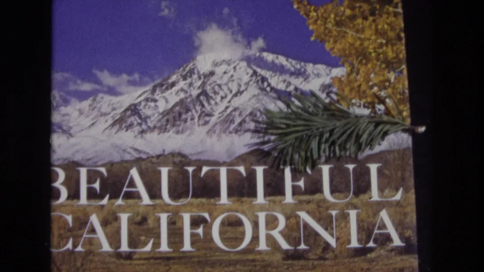 A second frame of the 1973 8mm Beautiful California title card shows the mountain artwork, large white lettering, evergreen branch, and autumn foliage partially divided by the film gate.