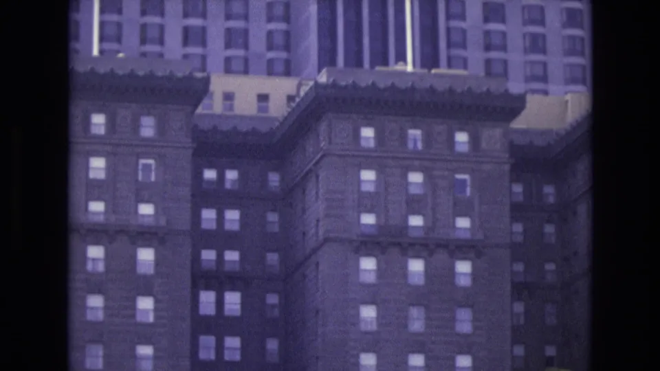 1973 San Francisco 8mm frame showing the upper portion of a tall ornate hotel building with many windows and a purple film tint.