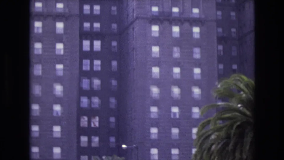 1973 San Francisco 8mm frame showing a downward view on the hotel exterior, with palm fronds and a streetlight visible near the lower edge.
