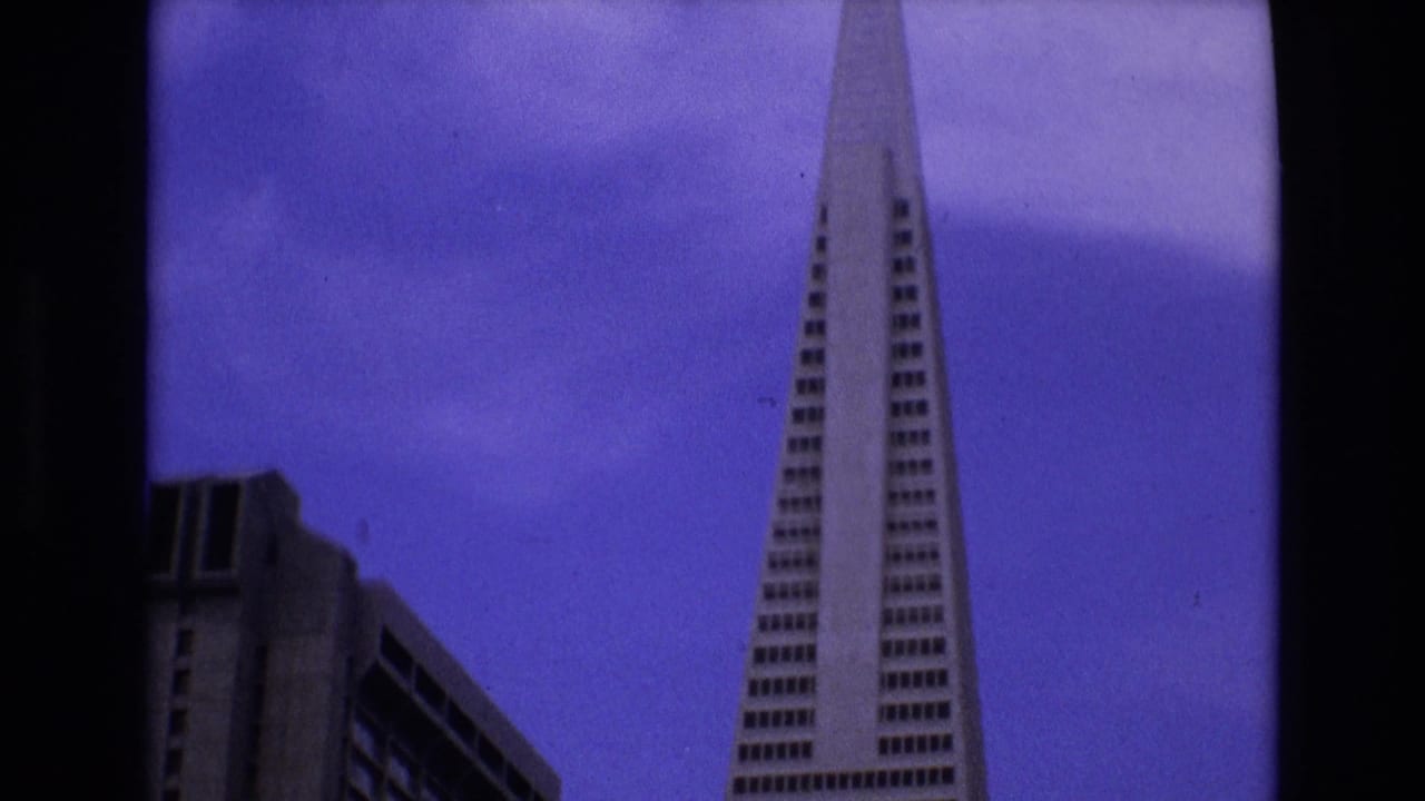 Tall pyramid-shaped skyscraper framed to the right with a lower building at left.