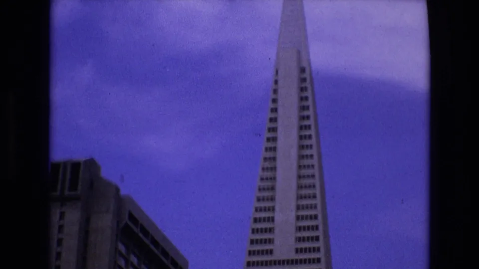 1973 San Francisco 8mm frame with the Transamerica Pyramid dominating the right side and a blocky downtown building partly visible at left.