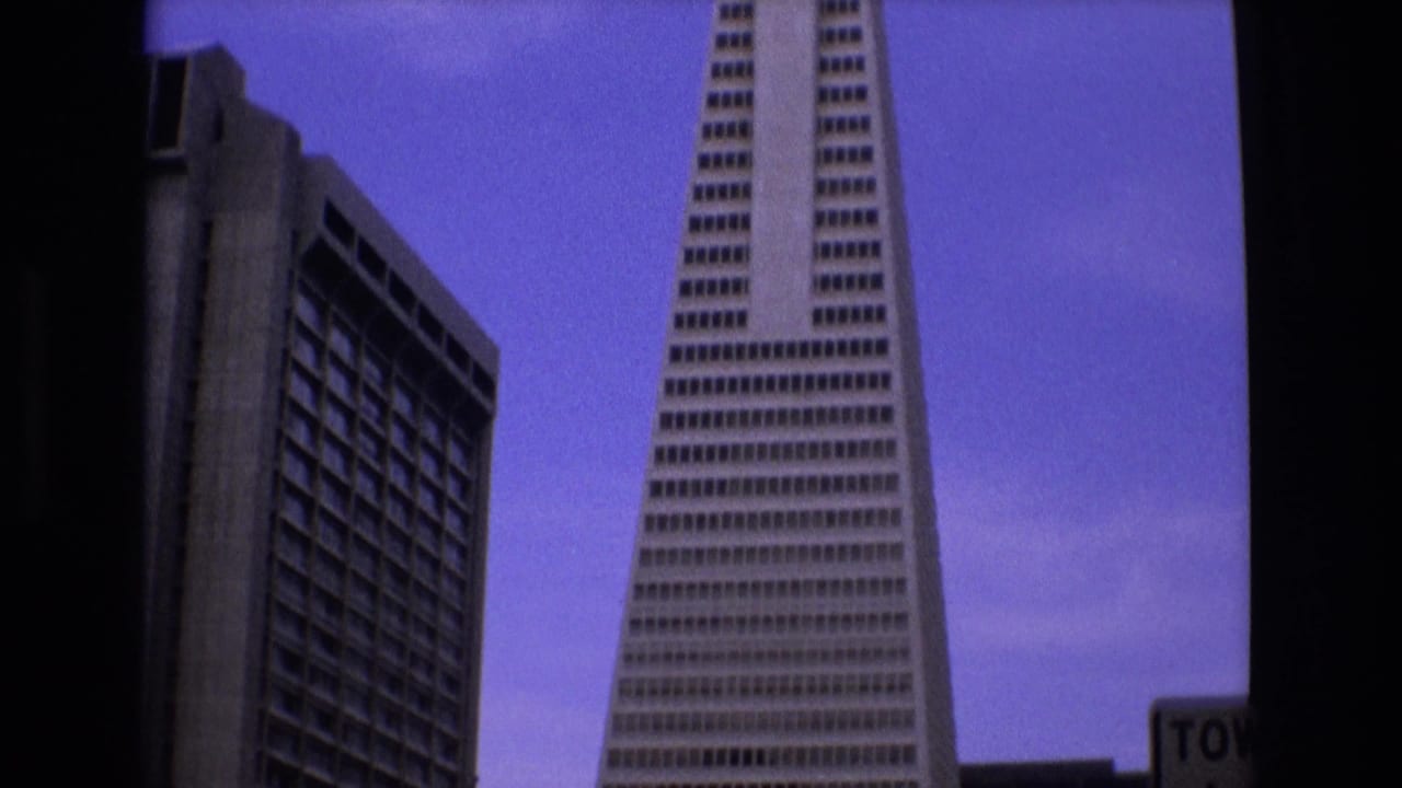 Low-angle view of the Transamerica Pyramid beside a rectangular high-rise under a blue-purple sky.