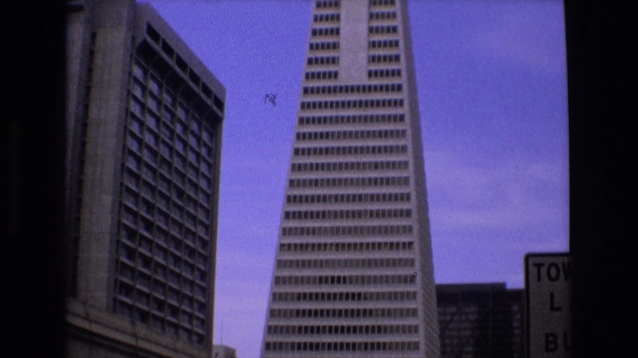 1973 San Francisco frame with the Transamerica Pyramid centered near a neighboring high-rise, with partial street signage at the right edge.