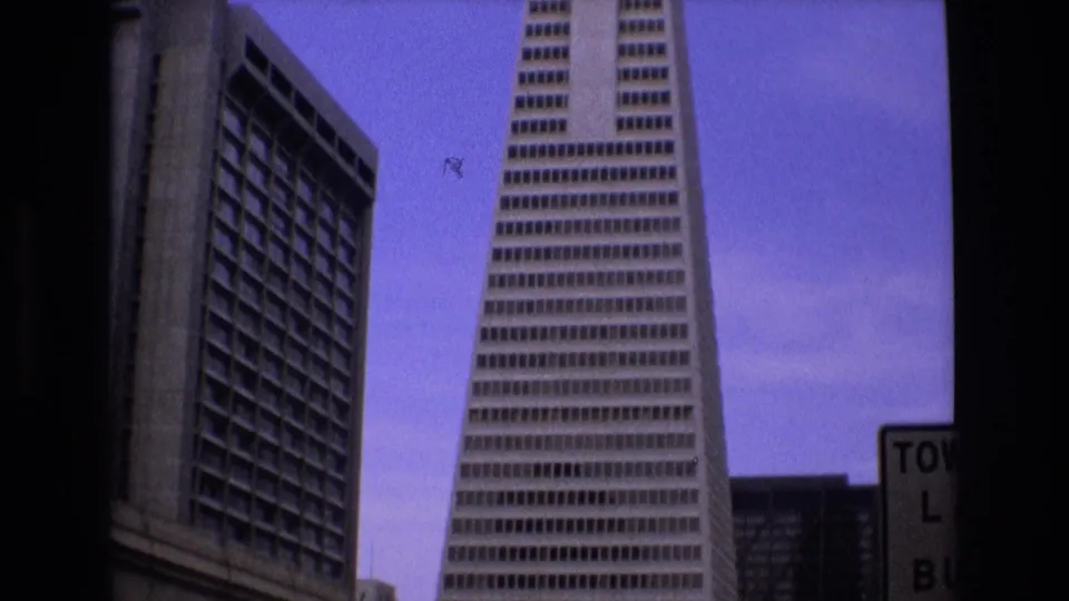 1973 San Francisco frame with the Transamerica Pyramid centered near a neighboring high-rise, with partial street signage at the right edge.