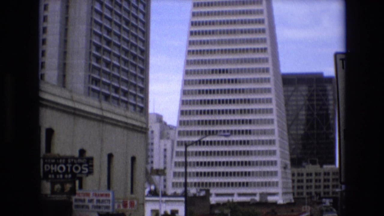 Downtown San Francisco buildings with the Transamerica Pyramid centered beyond street-level signs.