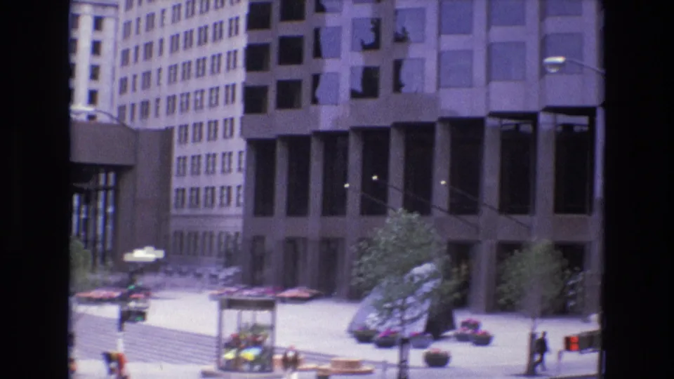 Soft 1973 San Francisco plaza view with tall office facades, young trees, a flower-filled kiosk, broad pavement, planters, and a lone pedestrian near the right edge.