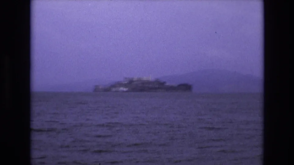 1973 San Francisco Bay view with Alcatraz Island in the distance, softened by haze, grain, and the purple-blue color shift of the 8mm scan.