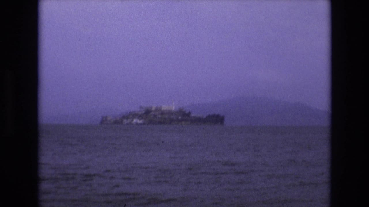 Small island structure seen across water under a hazy purple sky.