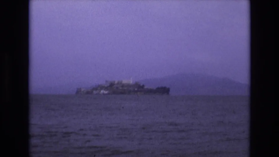 Distant view of Alcatraz Island from San Francisco Bay in a purple-tinted 1973 8mm home-movie frame.