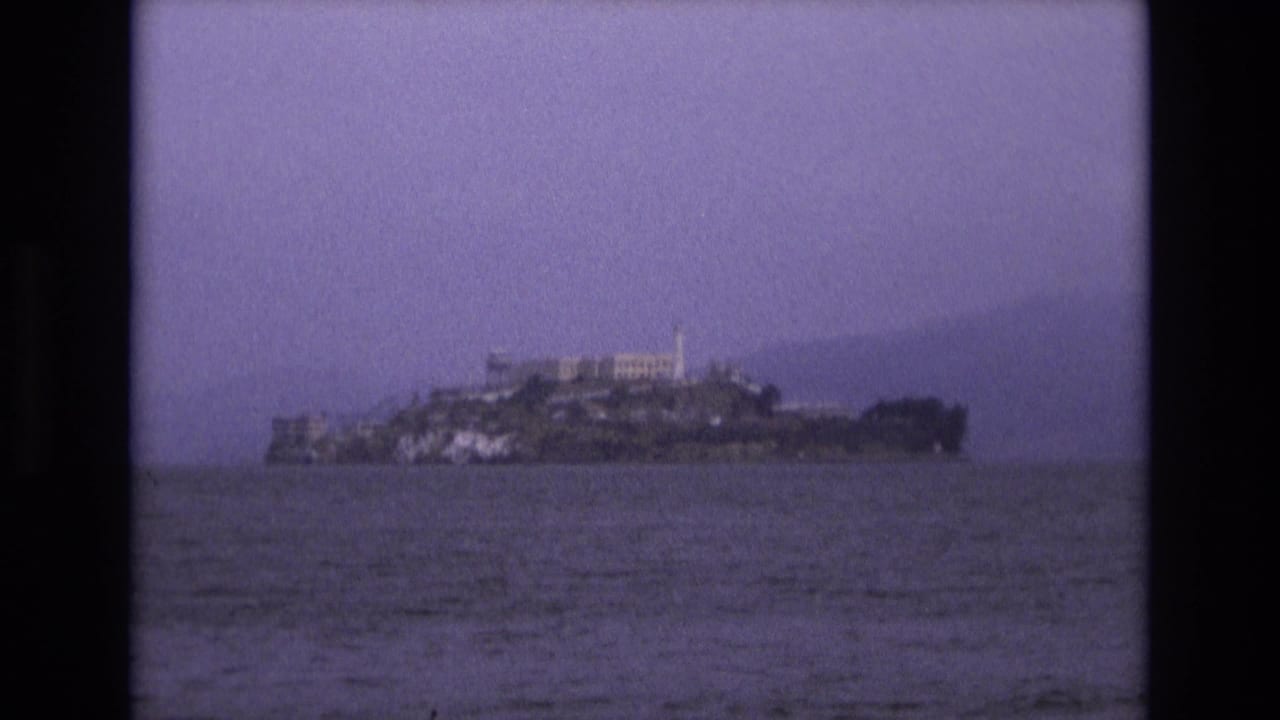 Distant Alcatraz Island across dark bay water under a hazy sky.