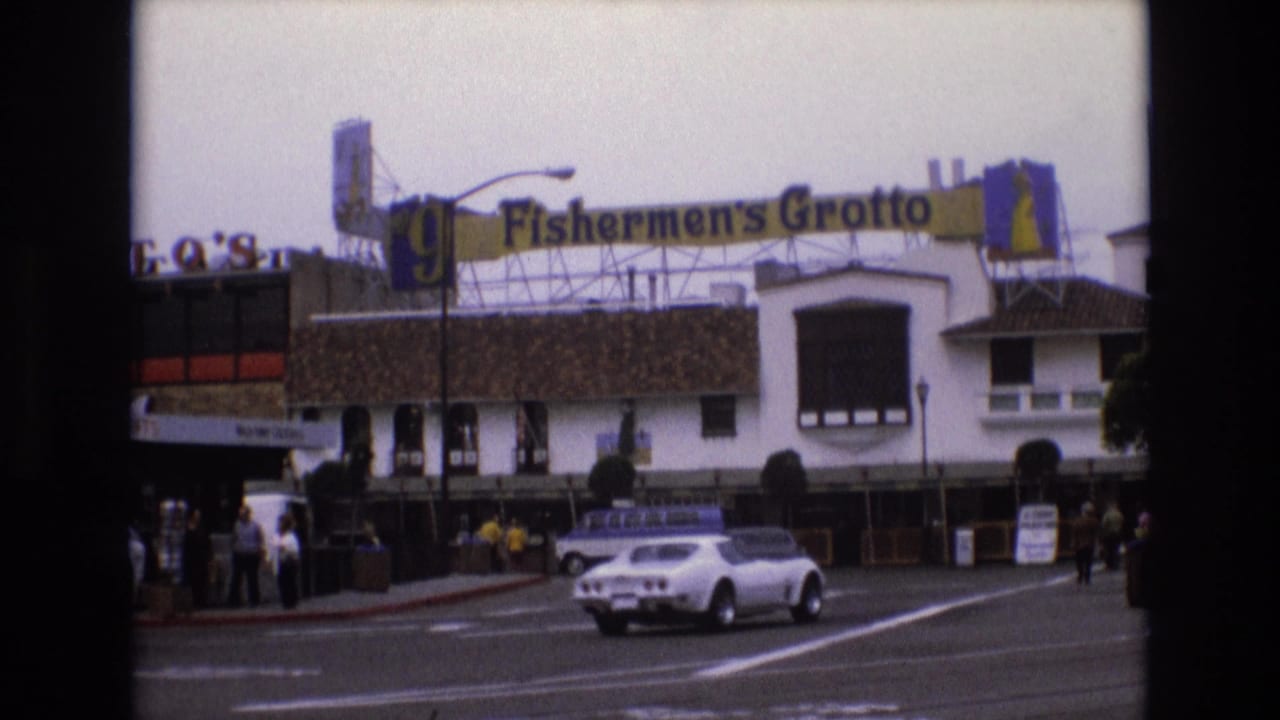 Fisherman's Grotto street facade with cars and pedestrians near the entrance.