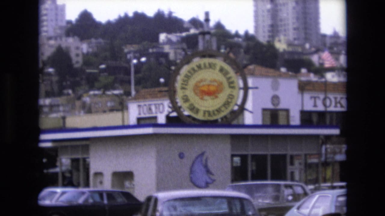 Fisherman's Wharf building with circular crab sign above parked cars.