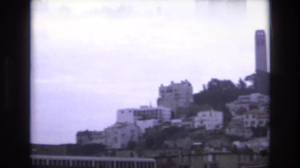 1973 San Francisco view toward Coit Tower, with hillside residences and trees seen through soft 8mm home-movie framing.