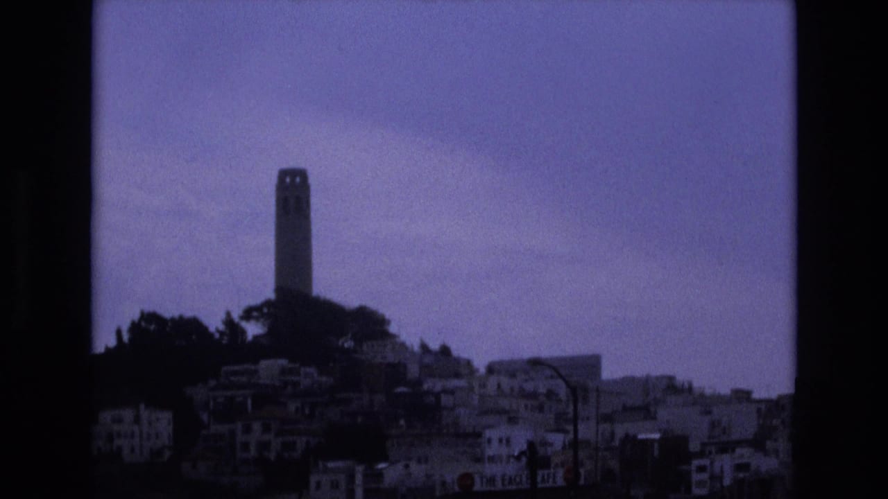 1973 San Francisco home-movie view of Coit Tower and surrounding hillside buildings, tinted blue-purple by the 8mm film scan.