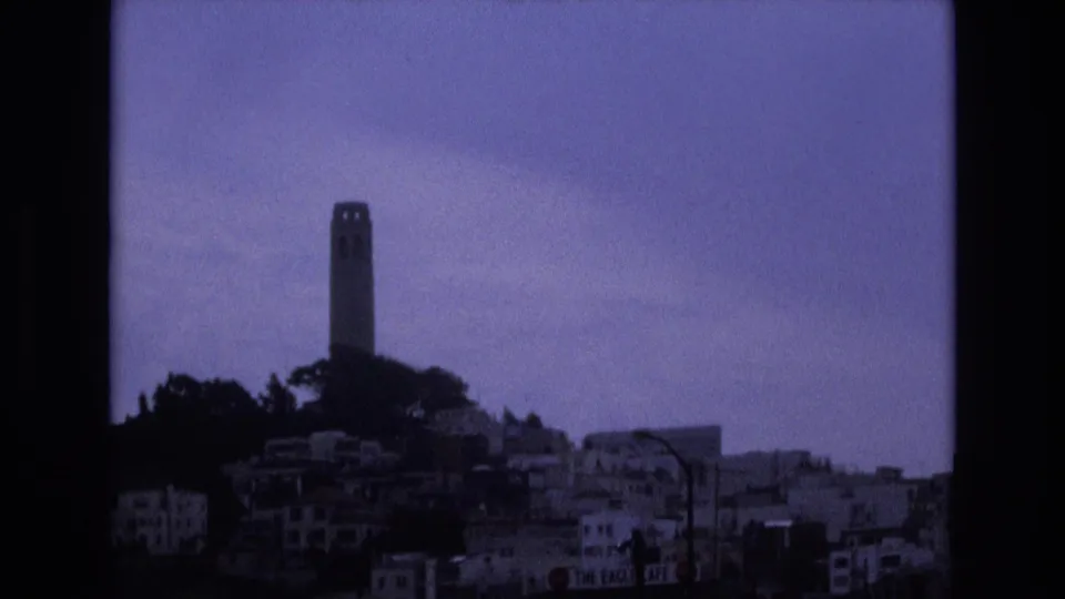 1973 San Francisco home-movie view of Coit Tower and surrounding hillside buildings, tinted blue-purple by the 8mm film scan.
