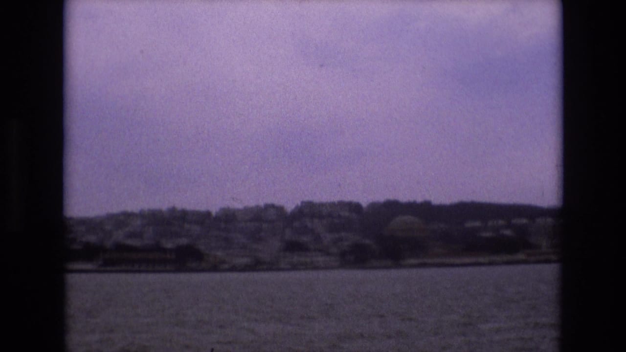 Hillside city shoreline across water with dark film borders.