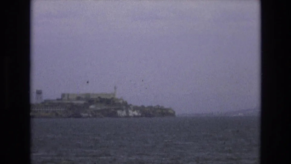 1973 8mm home-movie frame showing Alcatraz Island across the water from a moving boat on San Francisco Bay.