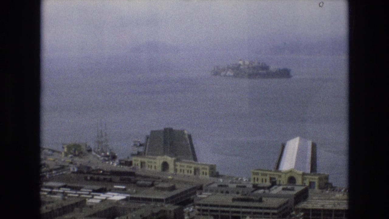 1973 8mm home-movie frame looking across San Francisco Bay from the Embarcadero area toward distant Alcatraz under a hazy sky.
