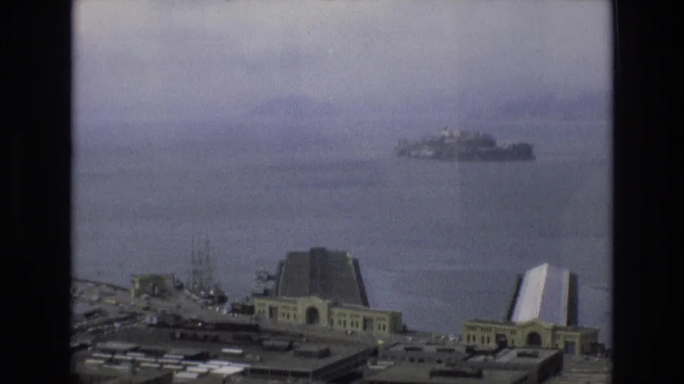 The final 1973 home-movie frame holds on the San Francisco waterfront, bay, and distant Alcatraz with visible 8mm grain and muted color.