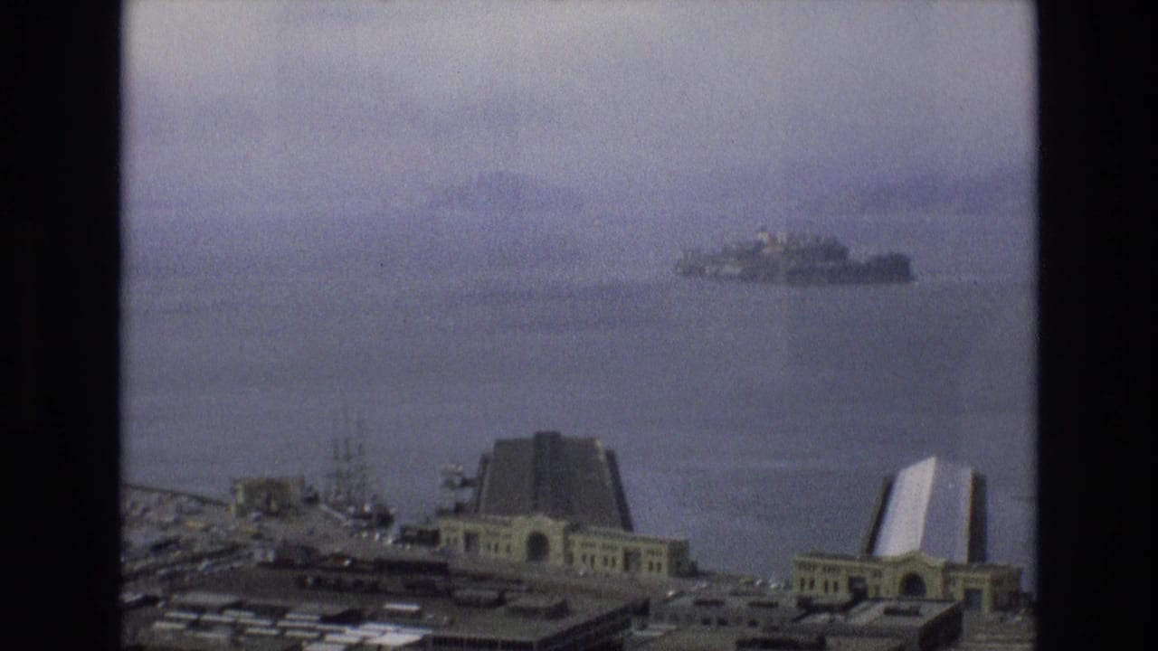 1973 San Francisco bayfront view from an elevated position, with shoreline buildings in the foreground and Alcatraz Island visible in the distance.