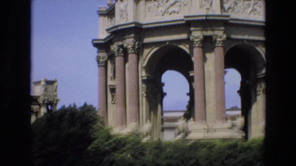 Handheld 8mm frame from 1973 showing the Palace of Fine Arts rotunda in San Francisco with multiple arches, tall columns, sculptural details, and dense greenery below.