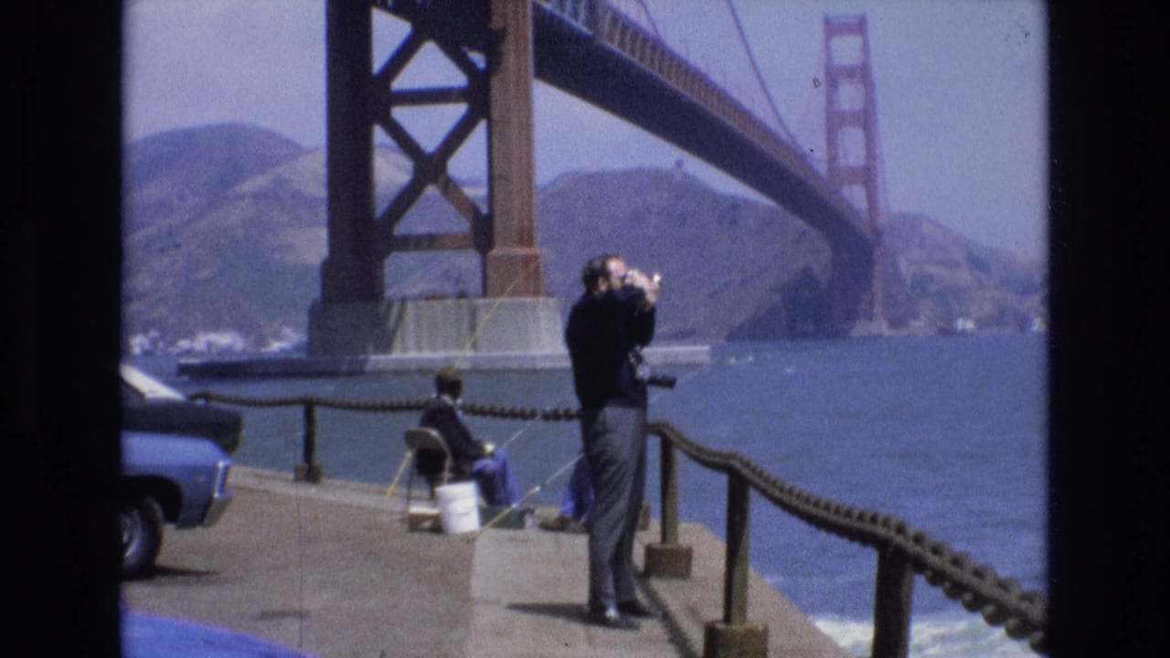 Man standing by pier railing with binoculars near the Golden Gate Bridge.