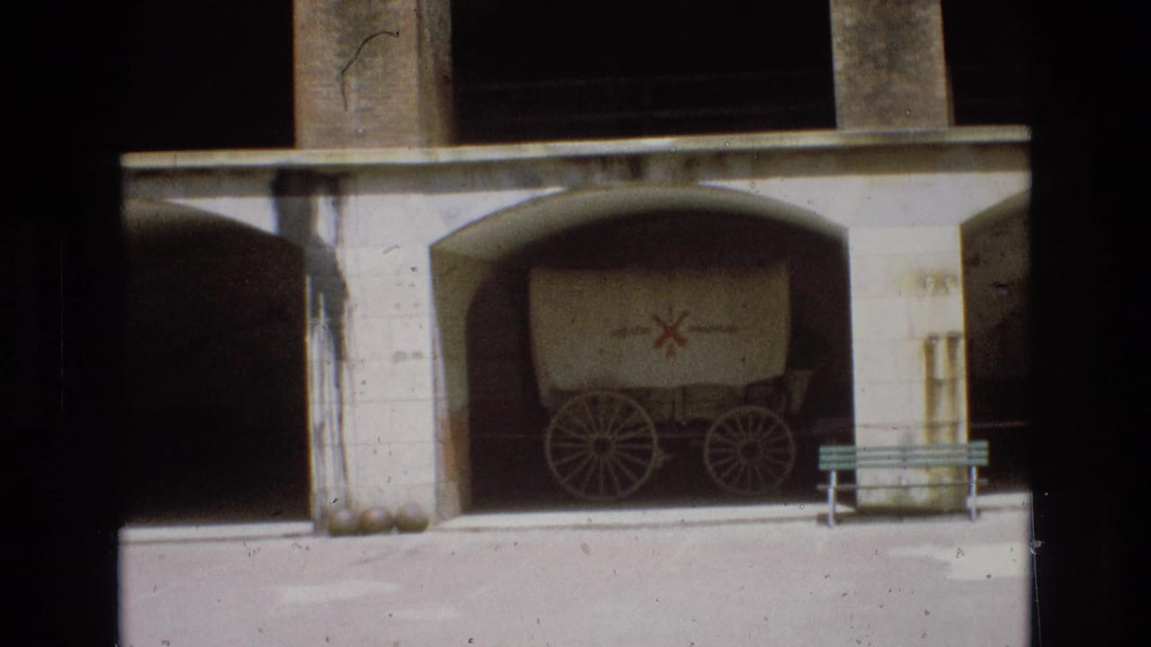 Covered wagon displayed under a concrete arch beside a bench.