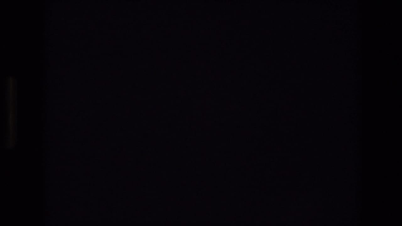 Underexposed 1974 8mm home-movie frame from Colorado Springs with mostly black image area and faint vertical film-frame edges before the sky becomes visible.