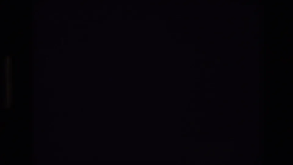 Underexposed 1974 8mm home-movie frame from Colorado Springs with mostly black image area and faint vertical film-frame edges before the sky becomes visible.