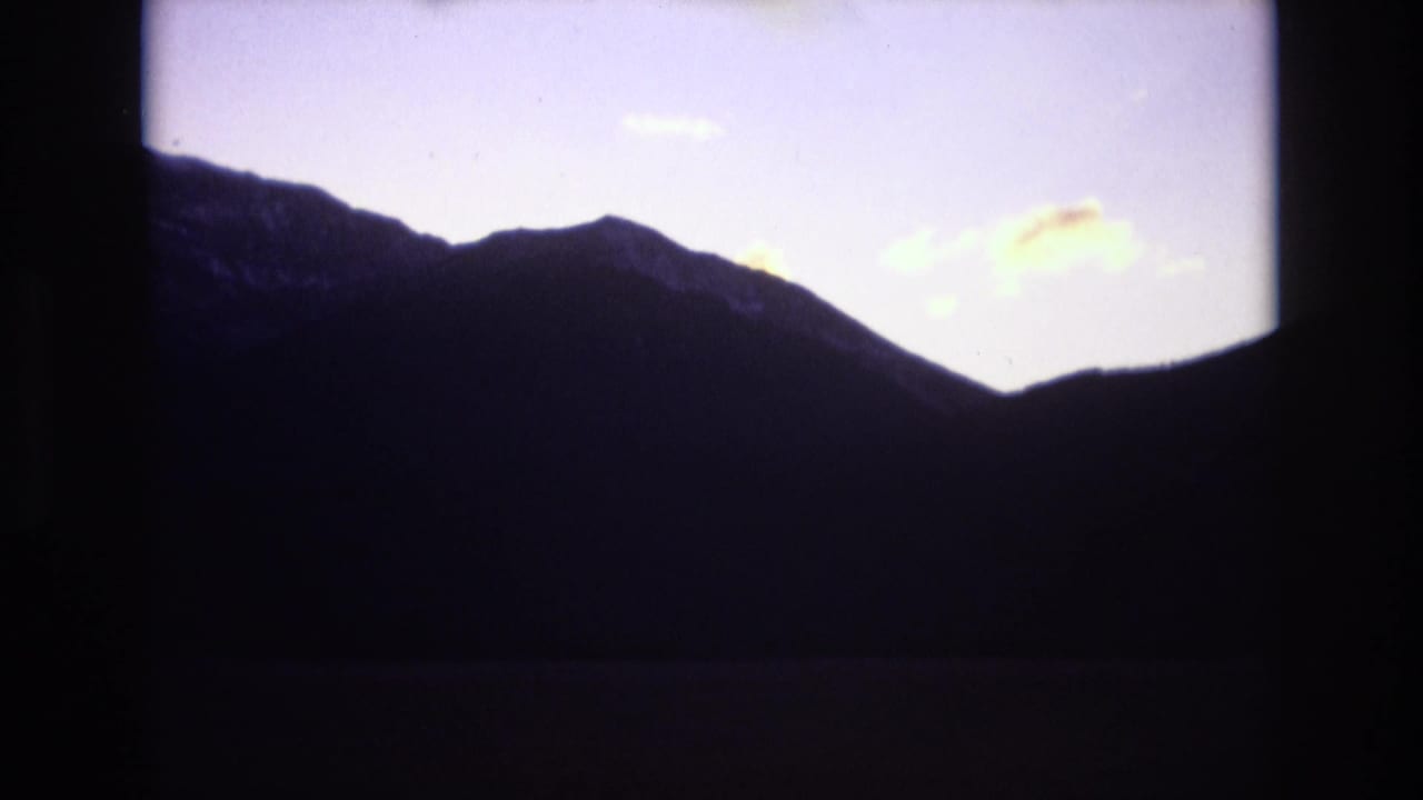 Jagged mountain silhouette below a pale evening sky and soft clouds.