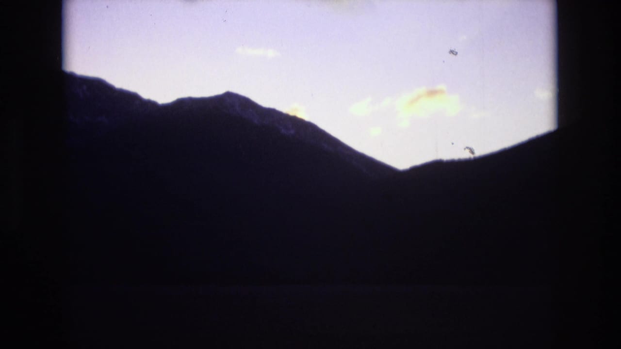 A shadowed mountain ridgeline sits below a fading purple sky with small light clouds, consistent with the Colorado Springs travel clip metadata.