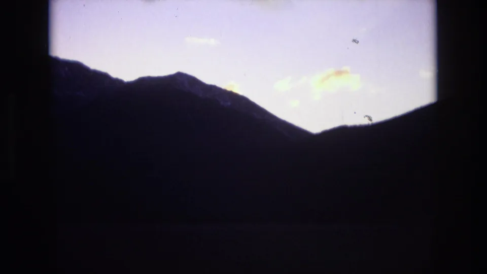 A shadowed mountain ridgeline sits below a fading purple sky with small light clouds, consistent with the Colorado Springs travel clip metadata.