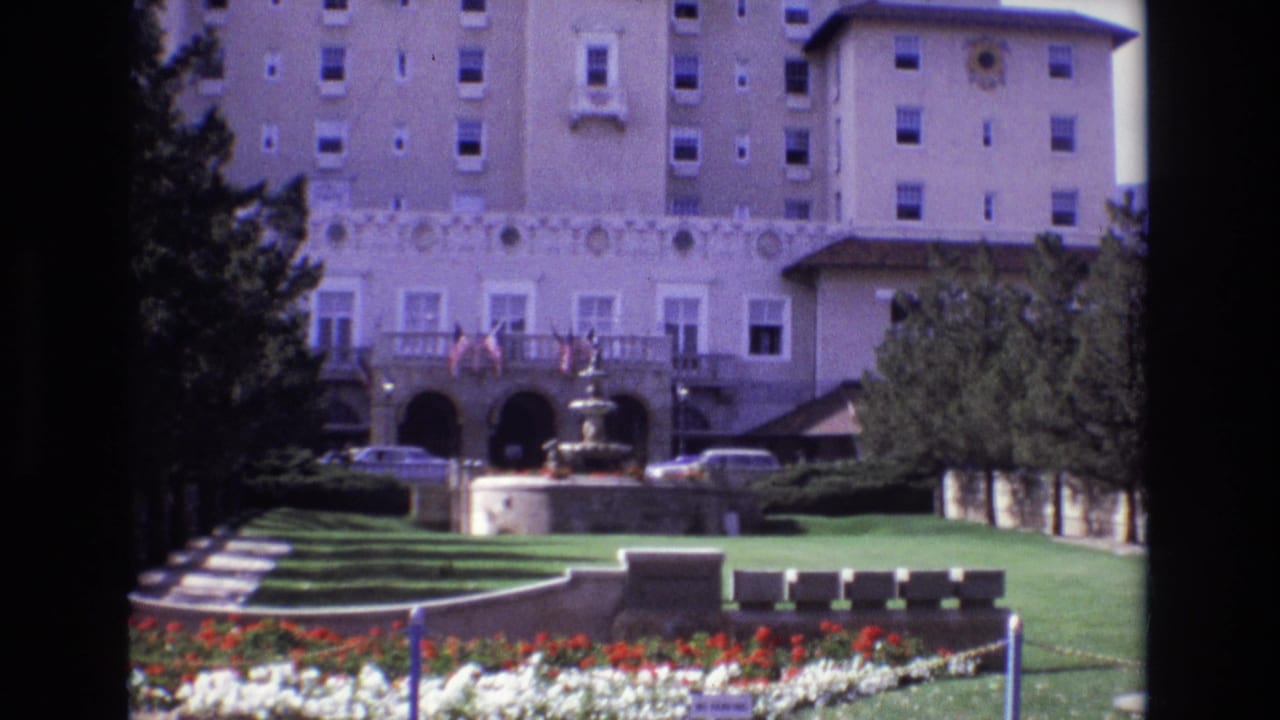 1974 Colorado Springs hotel garden view showing the fountain, formal lawns, flowerbeds, trees, parked cars, and the large resort facade.